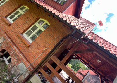 Montaż anteny Starlink na ceglanym budynku z kablem poprowadzonym po elewacji – HAKS Mrągowo, Mazury